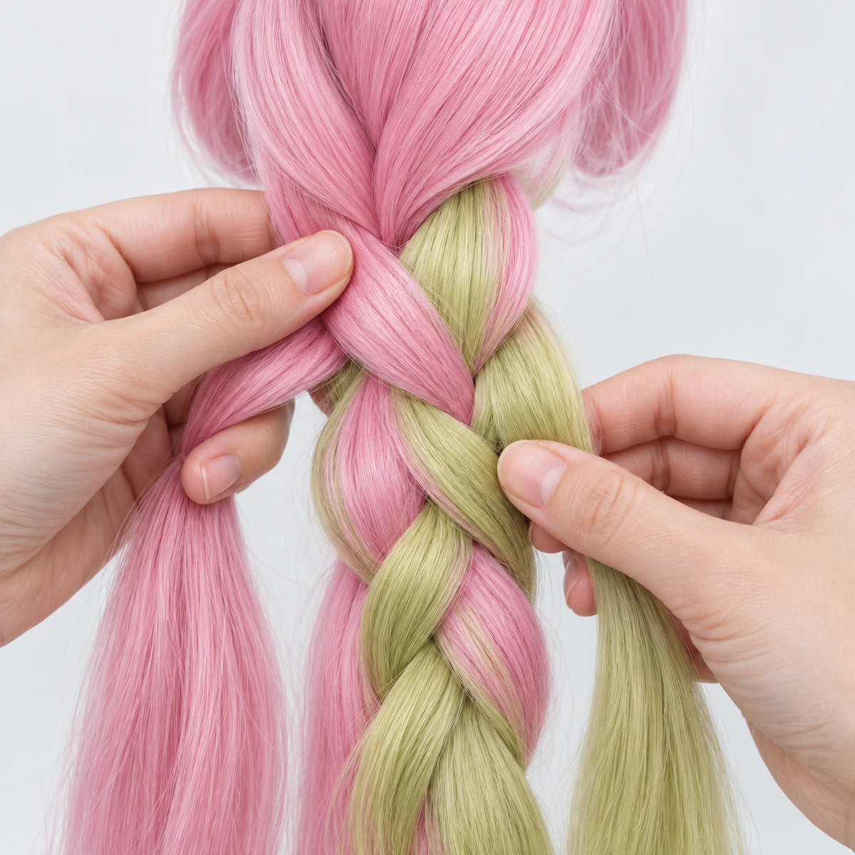 Hands braiding pink and green wig fibers; no face shown