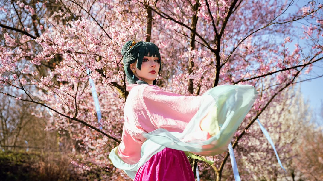 A stunning Maomao cosplay from The Apothecary Diaries featuring a high-quality pink and magenta costume by koollia, posed elegantly under blooming cherry blossoms.